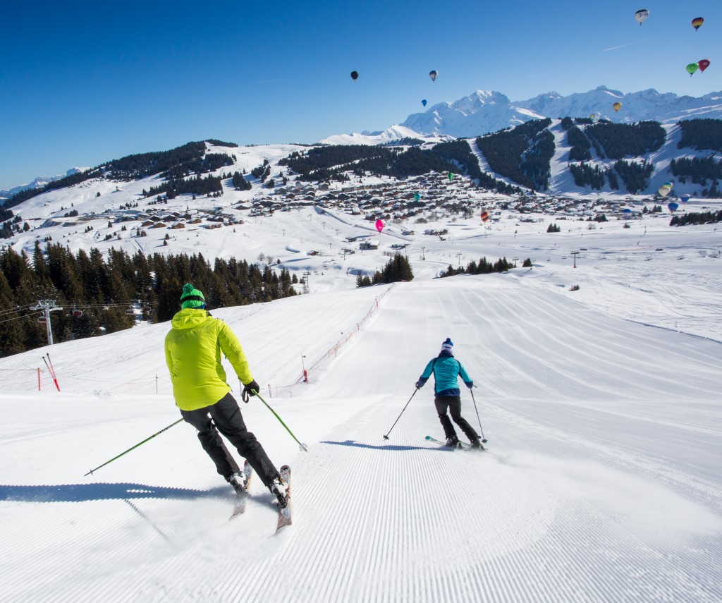 Skieurs sur une piste damée des Saisies avec vue panoramique sur la station